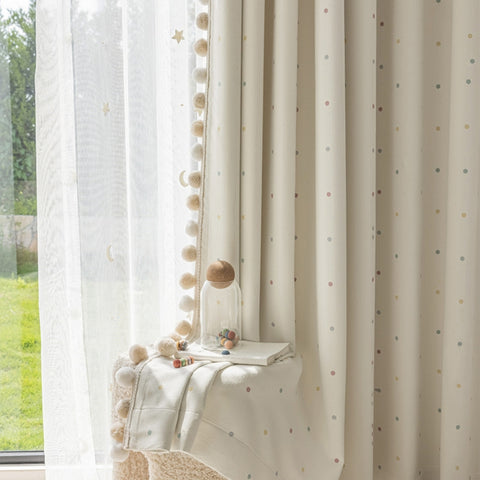 Cremefarbene Vorhänge für das Babyzimmer mit pastellfarbenen Punkten und Verdunklungsbommeln