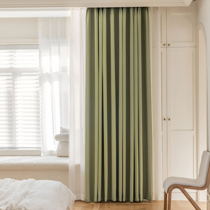 a bedroom with a white bed and green curtains