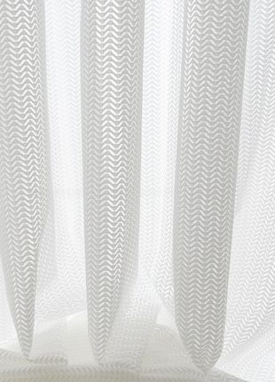 a close-up view of a white, sheer curtain with a repeating pattern of zigzag lines.