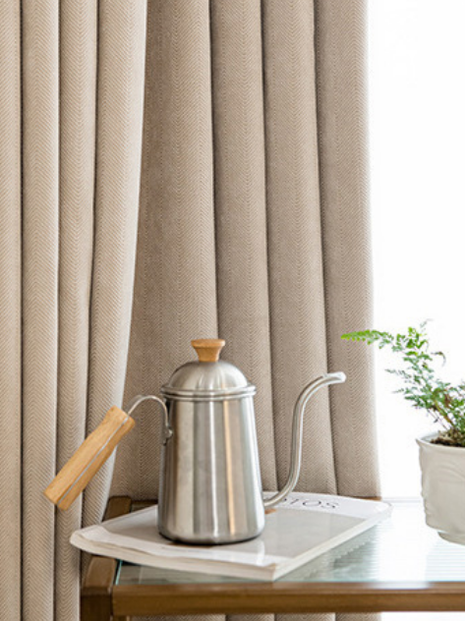 a silver kettle with a wooden handle, placed on a white tray, and a small potted plant next to it.