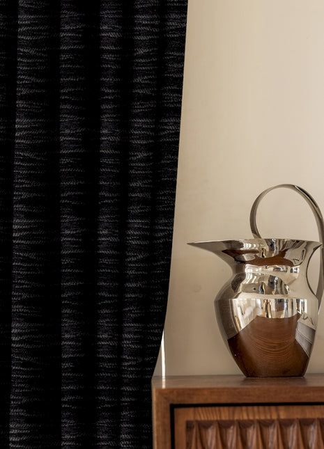 a silver vase sitting on top of a wooden table