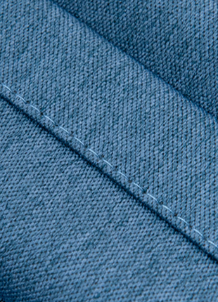 a close-up view of a blue fabric, possibly denim, with a diagonal stitching pattern.