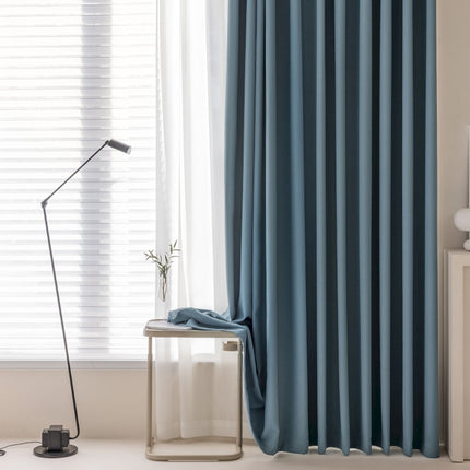 a living room with a lamp and a blue curtain