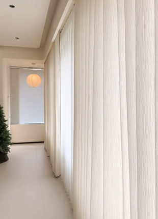 a hallway with a large window, white curtains, and a Christmas tree visible through the window.