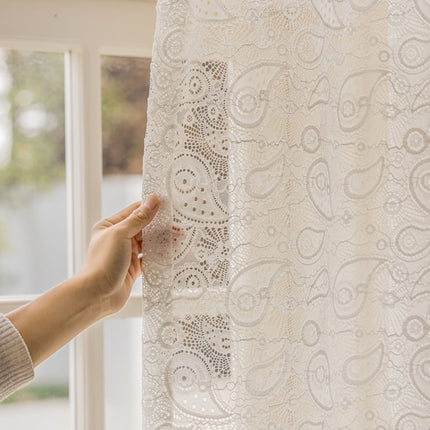 a person is holding a piece of lace in front of a window