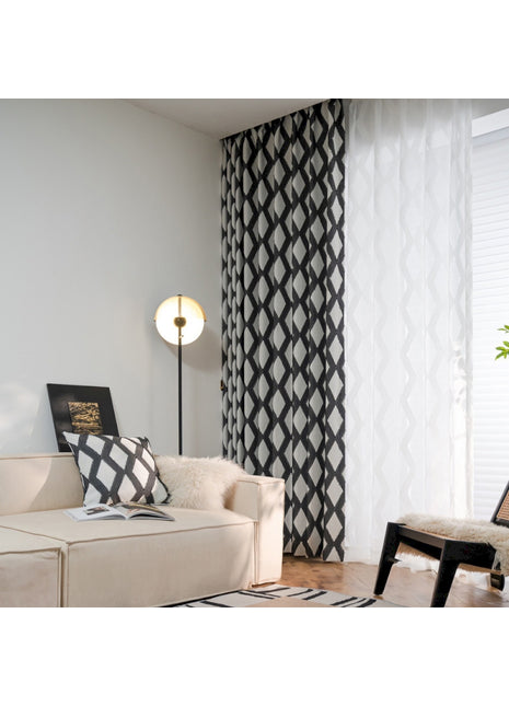ein Wohnzimmer mit weißem Sofa und schwarz-weißen Vorhängen