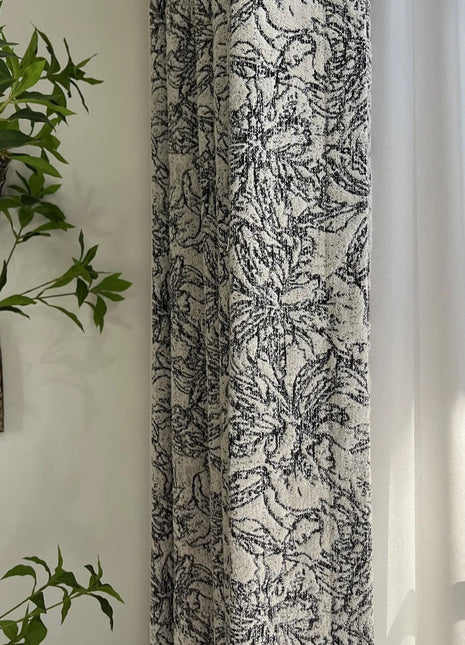 Neben einem Vorhang hängt eine Pflanze an der Wand.