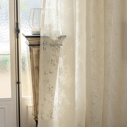 a window with a white curtain and a basket on top of it