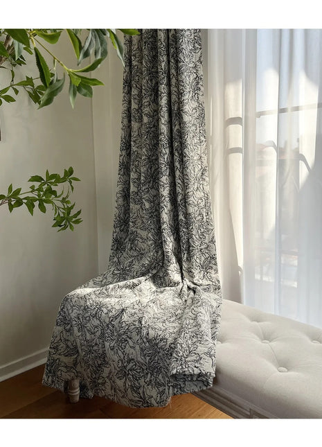 Ein weißes Sofa steht unter einem Fenster neben einer Pflanze.