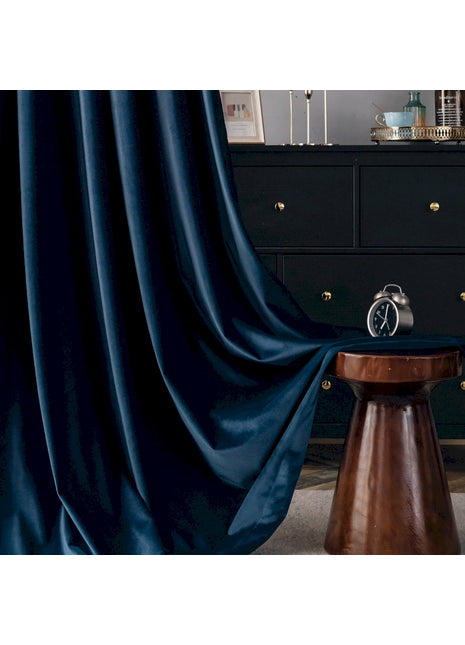 ein Zimmer mit einer schwarzen Kommode und einem blauen Vorhang