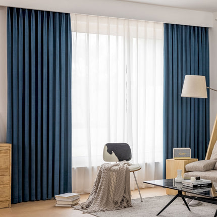 a living room filled with furniture and a window covered in blue curtains
