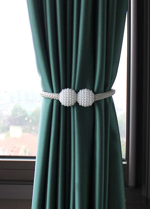 Une paire de perles blanches reposant sur un rideau vert, ajoutant une touche d'élégance à l'espace décoratif.