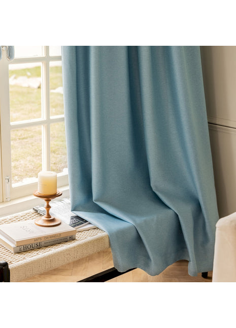 ein Fenster mit einem blauen Vorhang und einer Kerze
