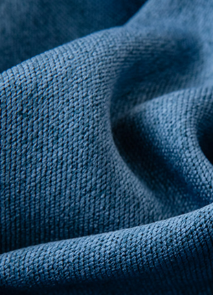 A close-up view of a crumpled blue fabric, with a textured and wrinkled appearance.