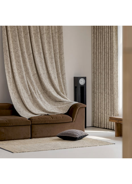 ein Wohnzimmer mit braunem Sofa und einem beigen Vorhang
