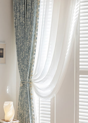 a bedroom with a window covered in white curtains