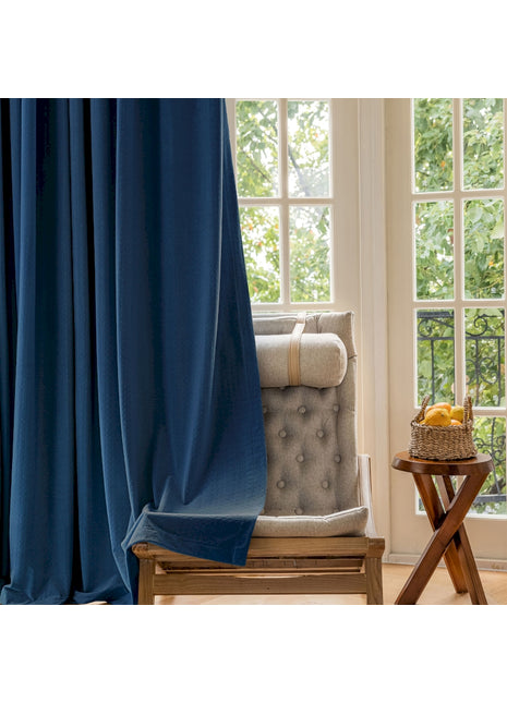 Ein Stuhl steht vor einem Fenster mit einem blauen Vorhang.