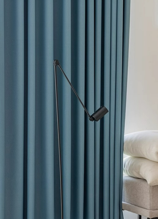 a modern living room with a blue curtain and a black floor lamp with a curved arm.
