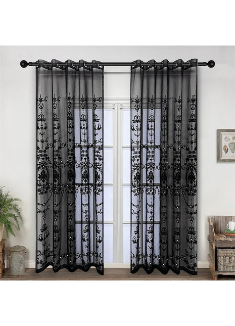 ein Wohnzimmer mit einem Fenster, das mit schwarzen, transparenten Vorhängen verhängt ist