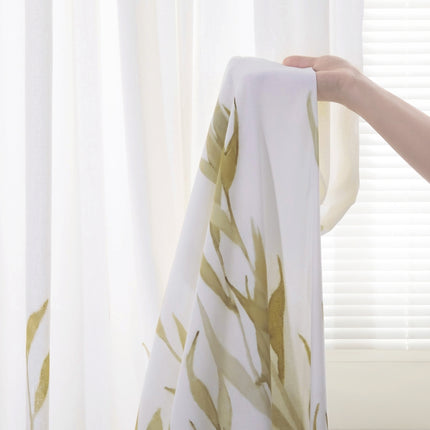 a person is holding a white curtain with gold leaves