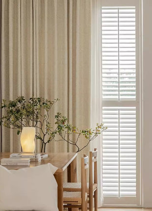 Rideau blanc cassé moderne dans une salle à manger claire, table et chaises en bois