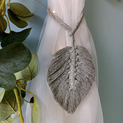 Un rideau blanc avec une feuille accrochée, mettant en valeur un style naturel et élégant. Corde d'attache disponible sur rideaux deco.